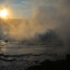 The Glaring Sun Sets Beyond The Churning Pool Of An Artemisia Geyser Eruption In Yellowstone National Park, Wyoming