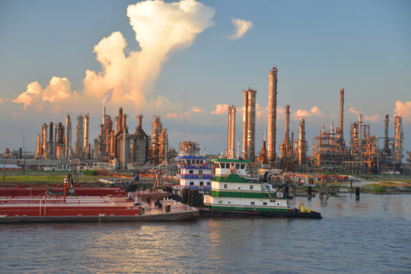 Sunset Light Enhances The Many Stacks And Towers Of The PBF Chalmette Refinery Beyond Barges Along The Mississippi River, Louisiana