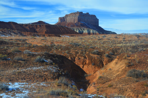 Wild Horse Butte Towers Over Its Colorfully Rugged Foothills Above Desert Scrub Brush Plains And Ravines In Remote South Central Utah