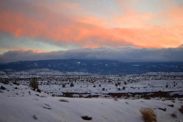 The Snowy Boulder Mountain Range Topped By White Clouds Under Higher Orange Clouds At Sunset Over Capitol Reef National Park, Utah