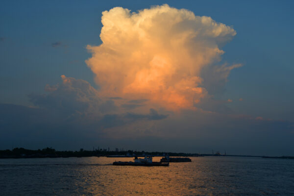 Boats Pass Each Other Across The Reflection Of A Massive Cumulonimbus Cloud At Sunset Over The Mississippi River Delta, Louisiana