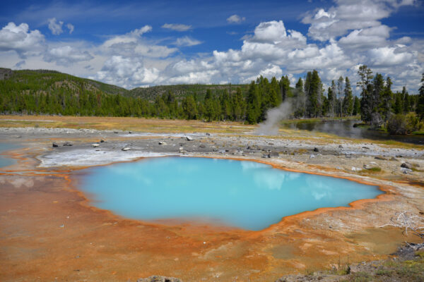 The Milky Blue Water Of Black Opal Pool Is Ringed By Orange And White Above The Firehole River In Biscuit Basin Of Yellowstone National Park, Wyoming