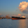 The Bulk Carrier Andrea Shulte Is Docked Near An Array Of Refinery Stacks Under Sunset Reddened Clouds Over The Mississippi Delta, Louisiana